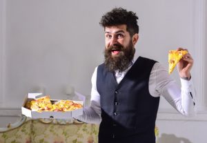 Man with beard and mustache holds box with tasty fresh hot pizza. Food delivery concept. Macho in classic clothes hungry, holds slice of cheese pizza